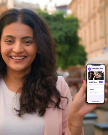 A young woman holding up her phone and smiling