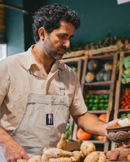 A grocer arranging fresh vegetables in his shop
